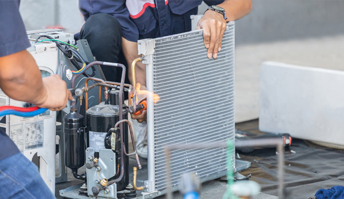 AC repair and maintenance technicians servicing an air conditioning unit.